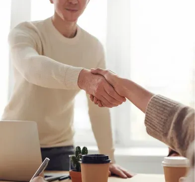 Two people shaking hands across a desk