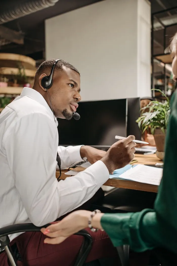 Contact centre agent in a headset reviewing documents with a colleague
